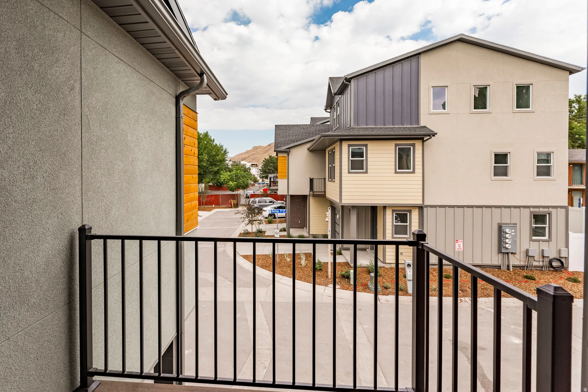 Balcony with a black metal railing and concrete flooring, overlooking a paved walkway