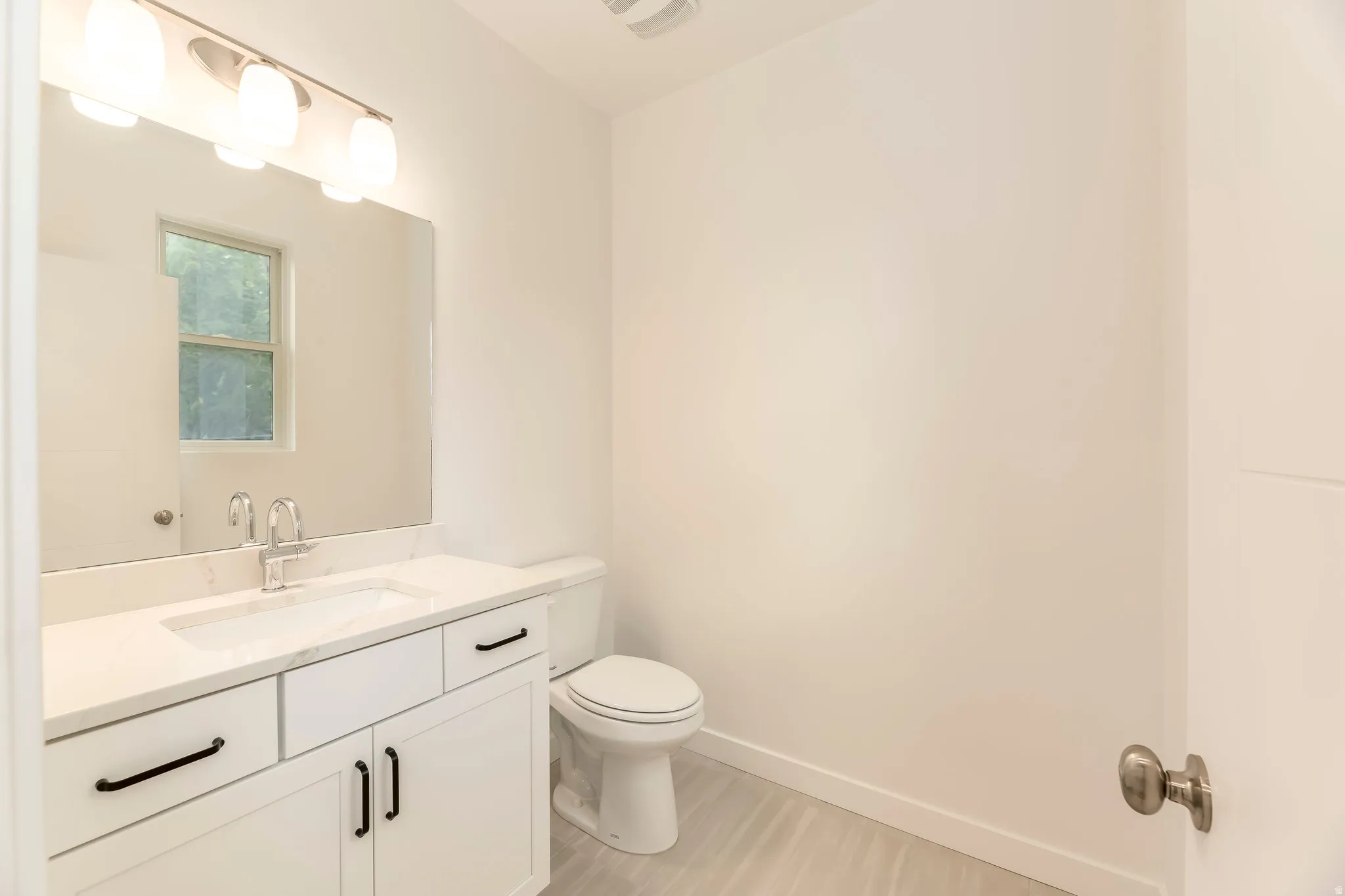 White vanity with integrated sink, stone-finish countertop, and matte black hardware