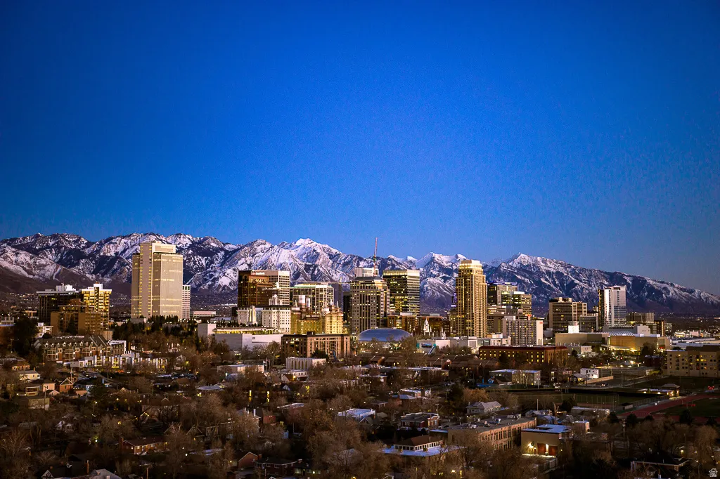 Downtown cityscape with illuminated buildings set against a snow-capped mountain range