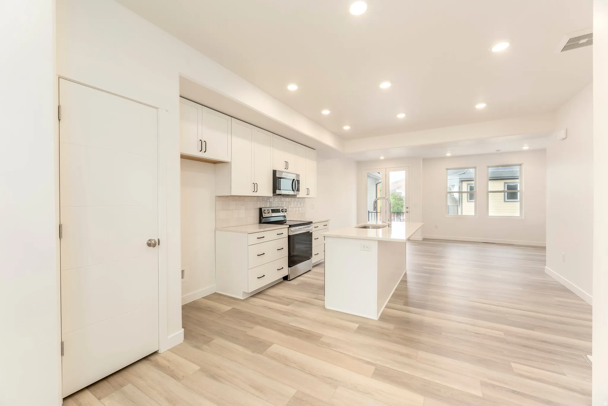 Kitchen featuring a central island with sink, white shaker-style cabinetry, and stainless steel appliances
