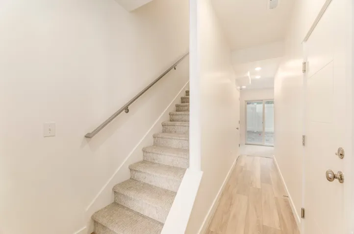 Light-toned wood-finish flooring, recessed lighting, and a modern white door with horizontal paneling