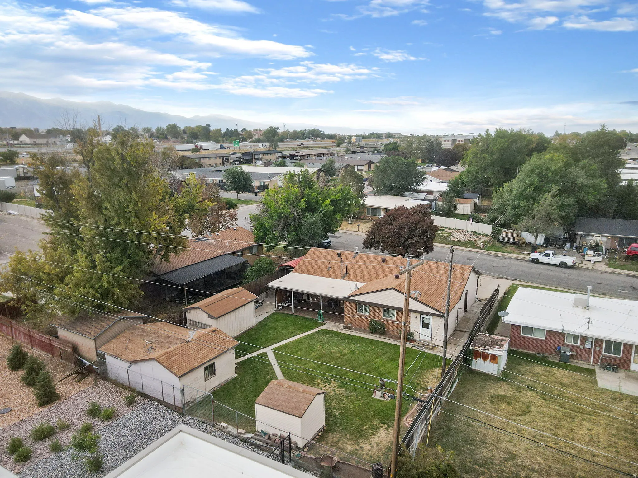 Expansive backyard featuring a manicured lawn, multiple outbuildings, and a covered patio area