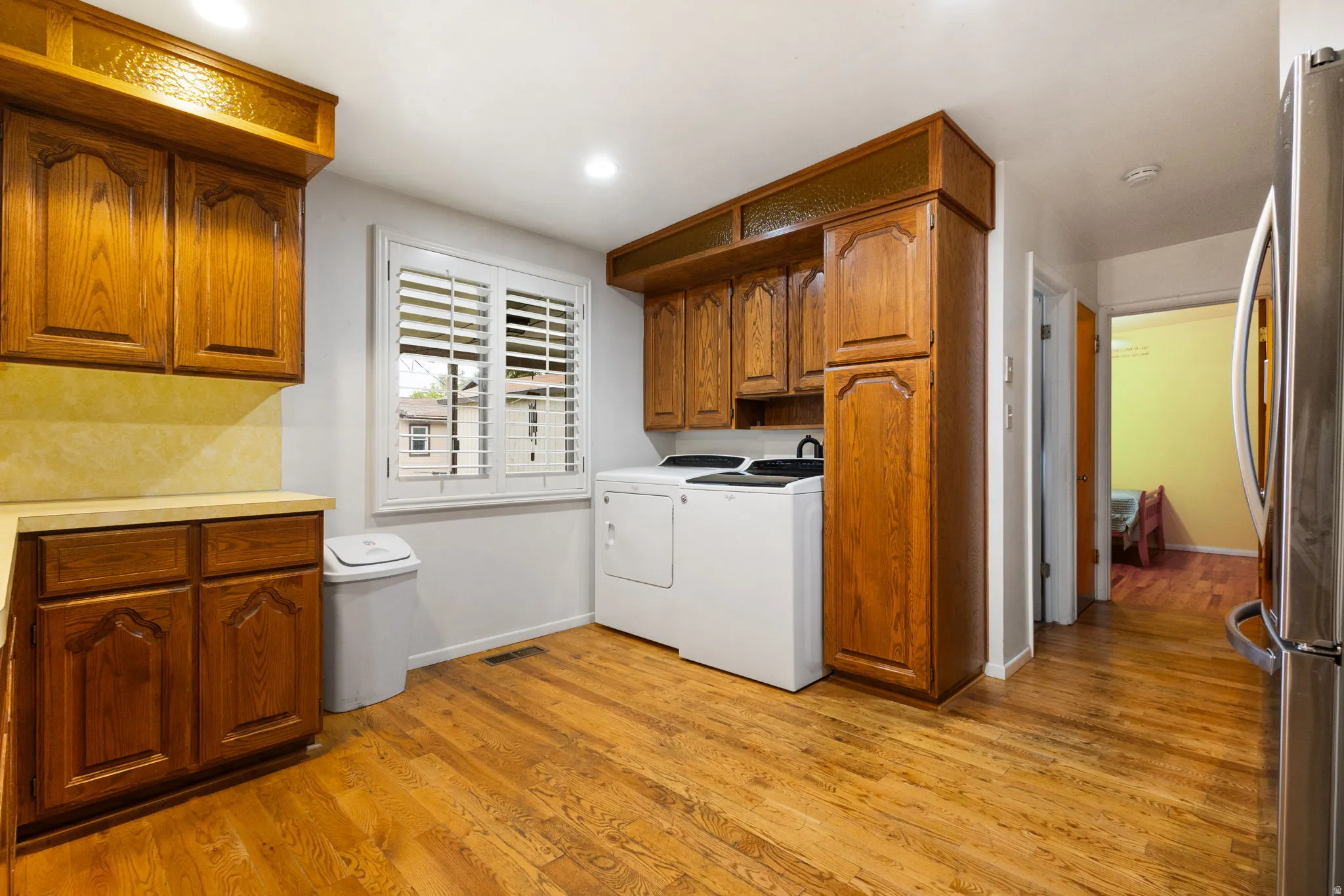 Wood-finish flooring throughout, solid wood cabinetry, ample counter space, recessed lighting, and a window with plantation shutters