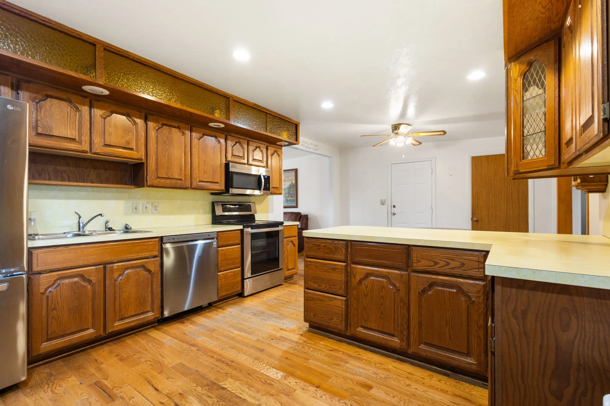 Wood-finish flooring, wood cabinetry, stainless steel appliances, recessed lighting, and a ceiling fan