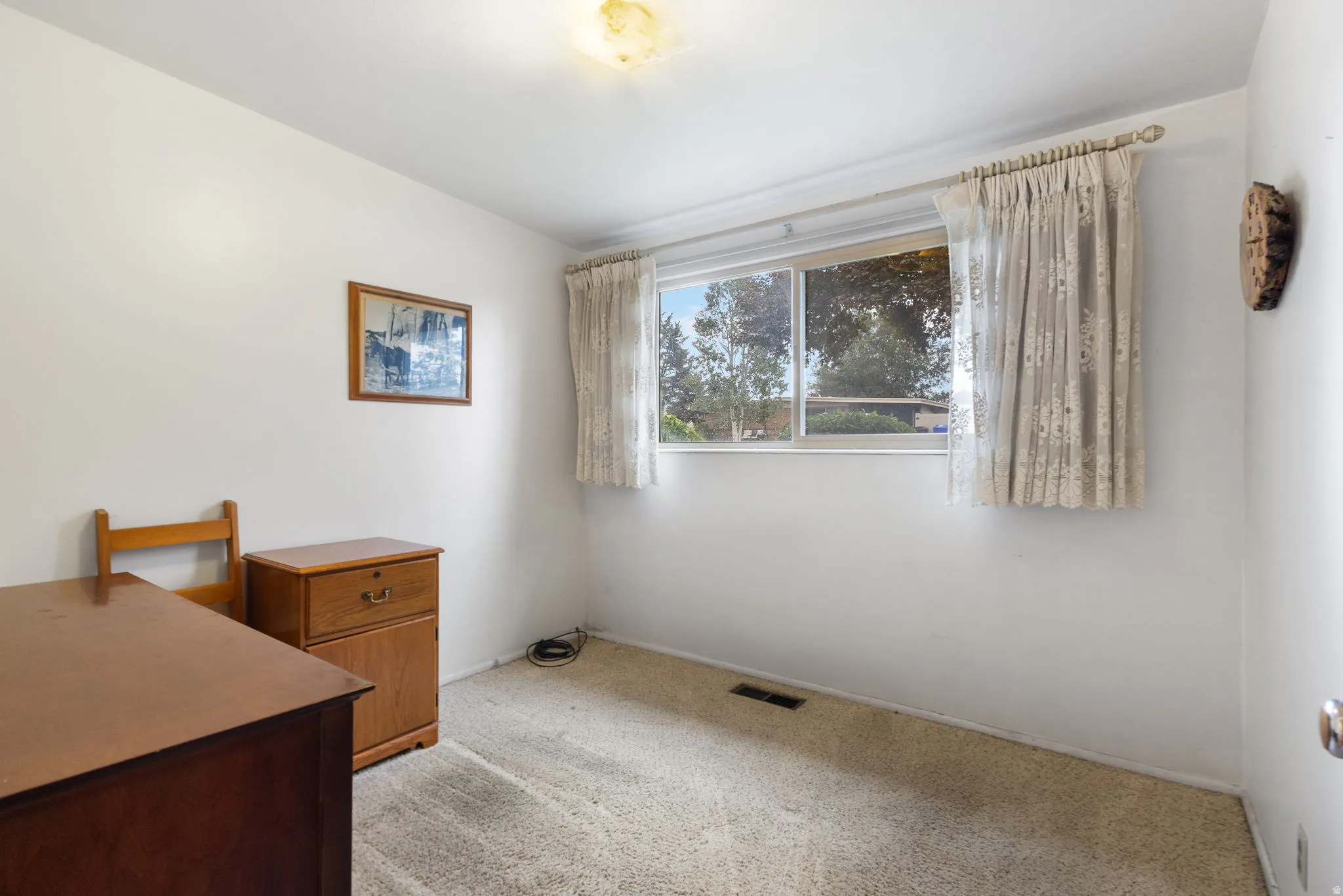 Carpeted room with a single window, white walls, and a ceiling-mounted light fixture