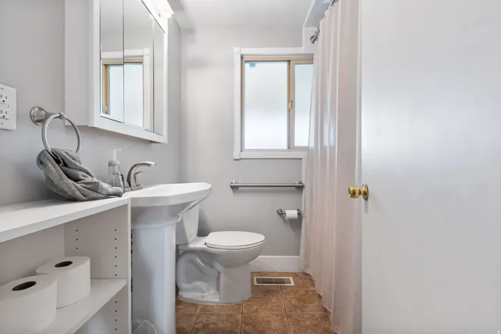 Bathroom featuring a pedestal sink, wall-mounted medicine cabinet, frosted window, and tiled flooring