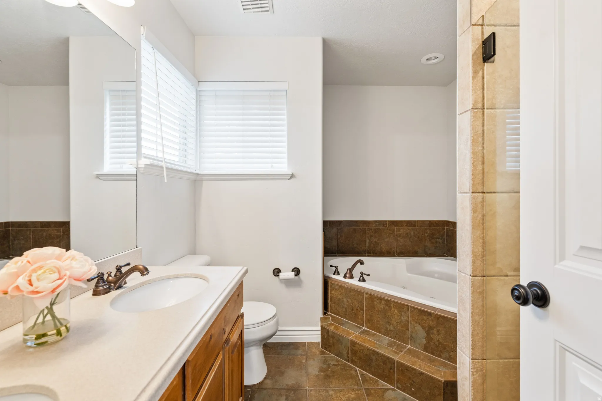 Double vanity with integrated sinks, oil-rubbed bronze fixtures, and wood-finish cabinetry