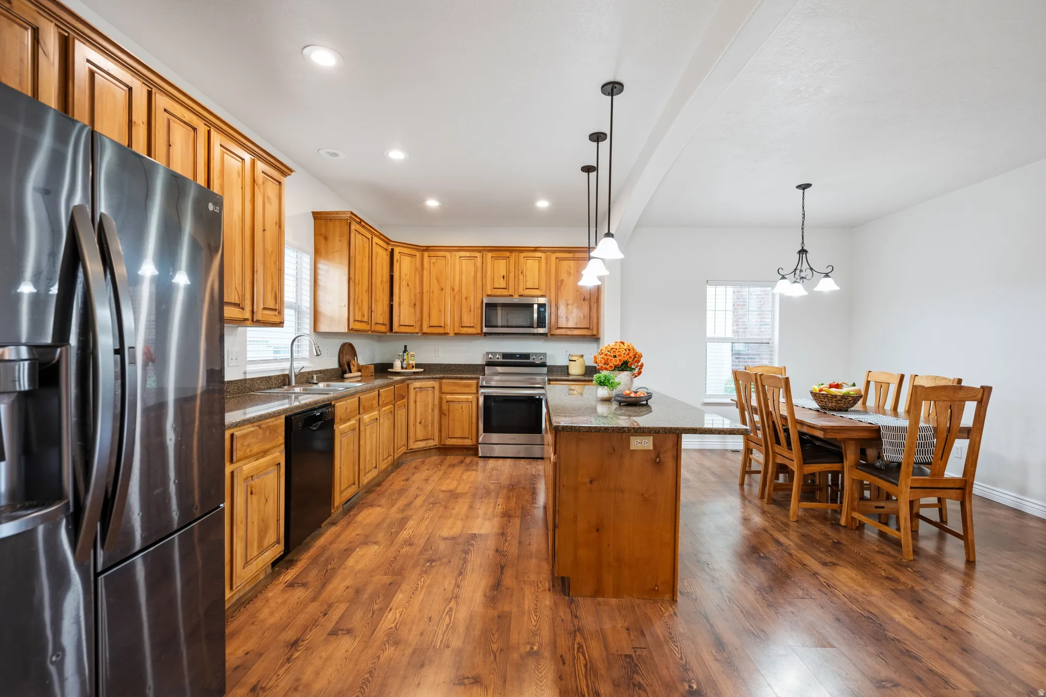 Kitchen featuring wood-finish flooring, recessed lighting, wood cabinetry, stone countertops, and a stainless steel appliance suite
