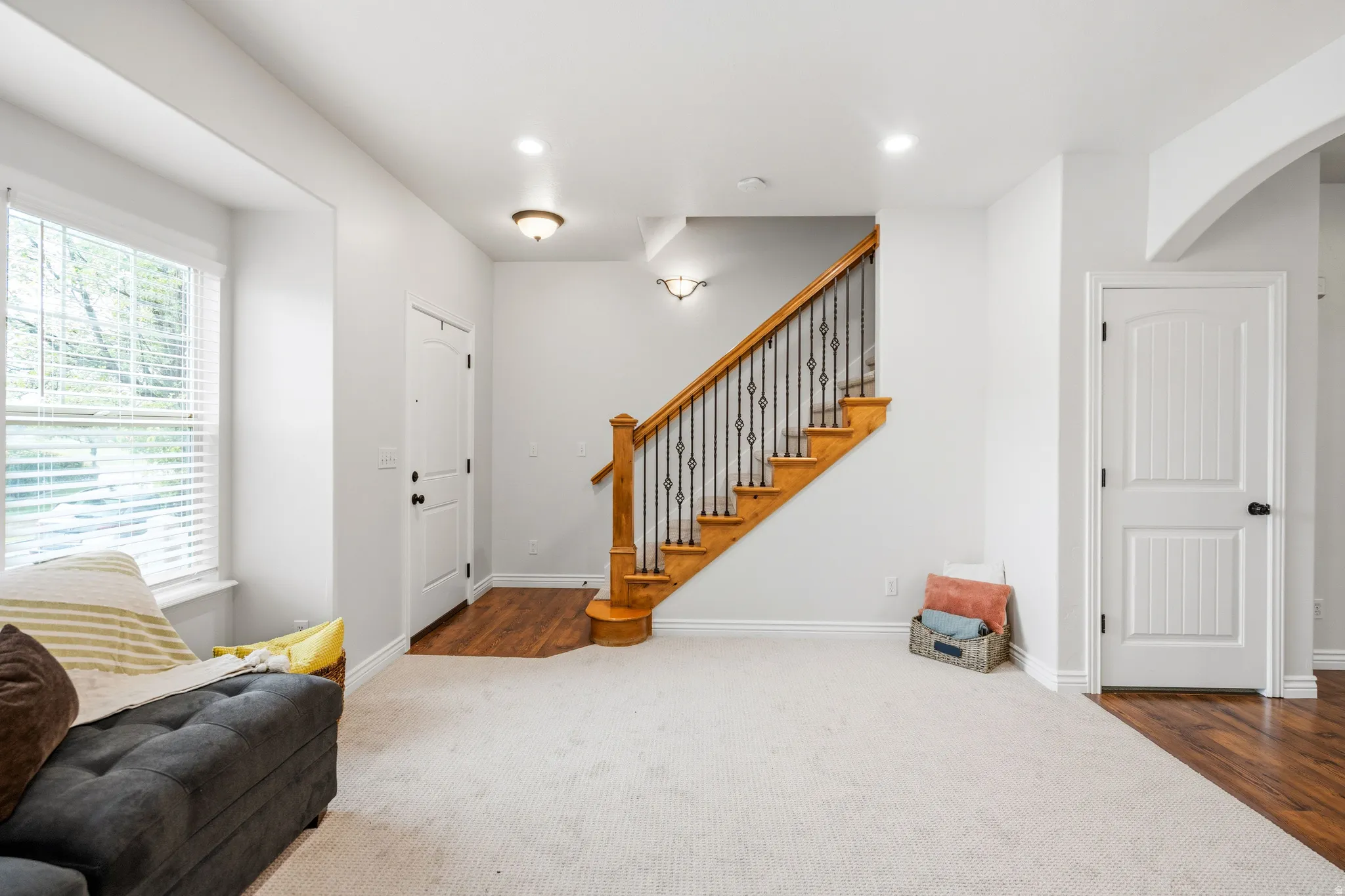 Staircase with wood treads and wrought iron balusters, white paneled doors, recessed lighting, and wood-finish flooring