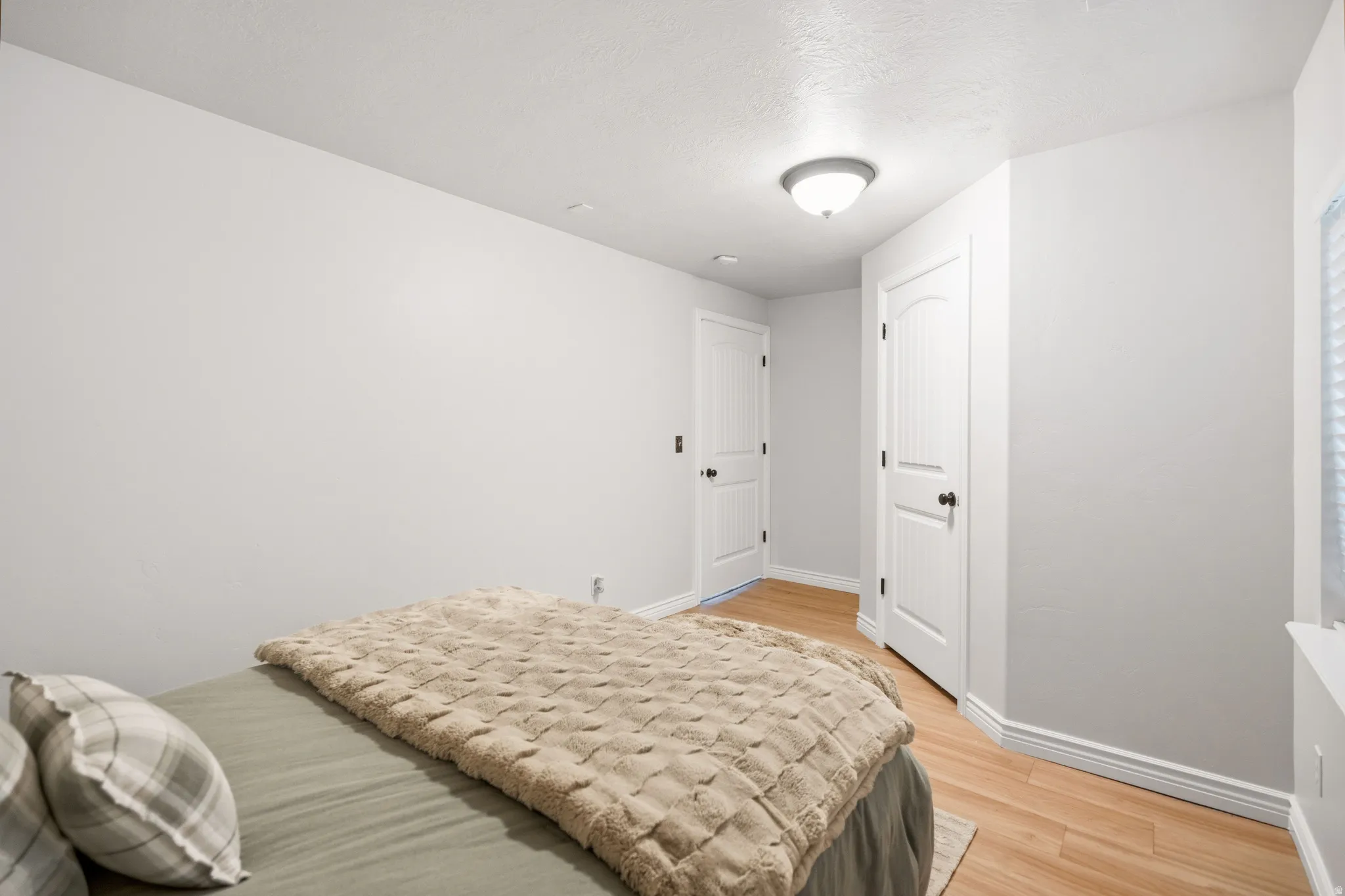 Wood-finish flooring, white walls, and a ceiling-mounted light fixture