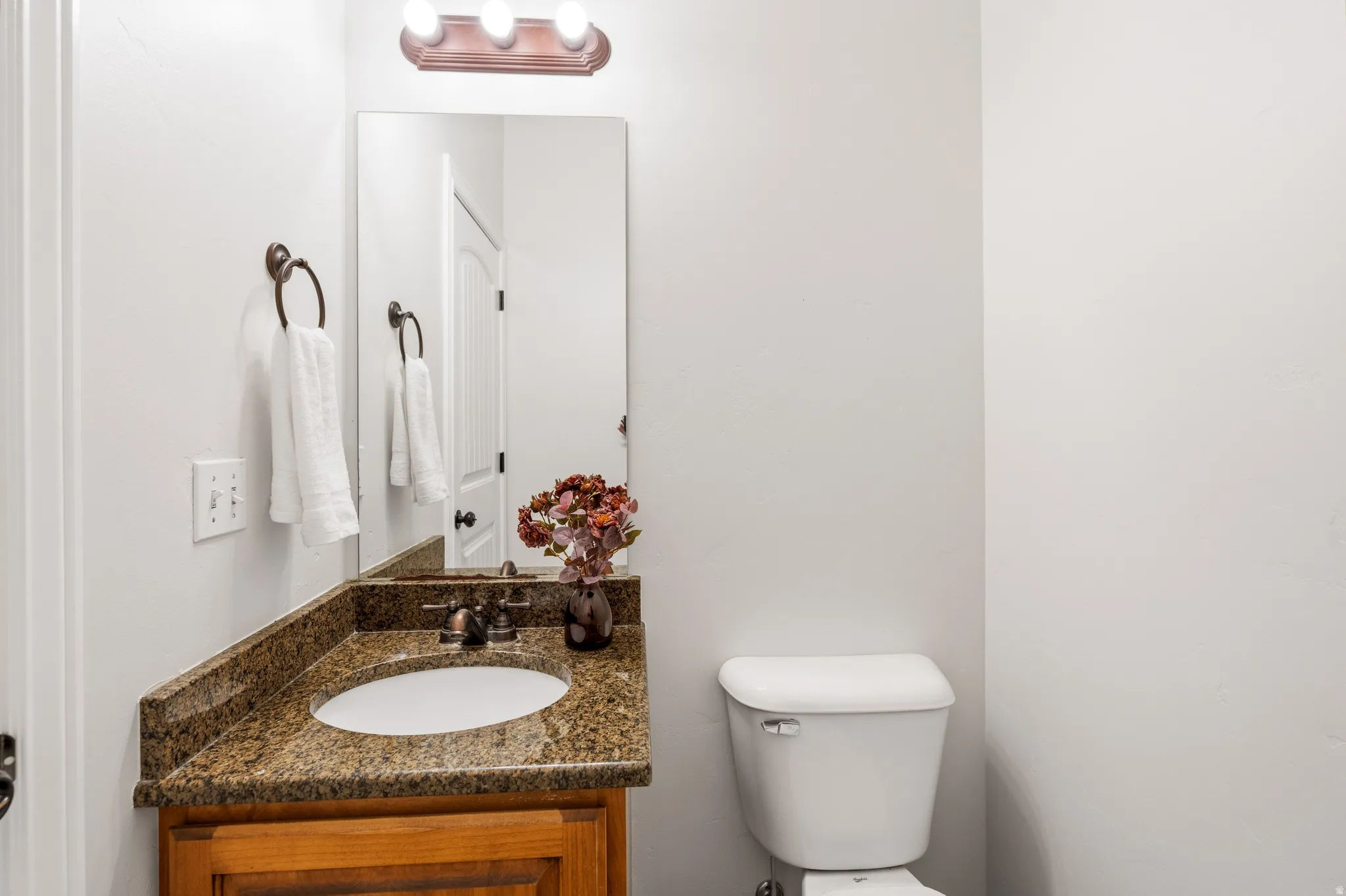 Wood-finish vanity with an undermount sink, stone countertop, and bronze-finish fixtures