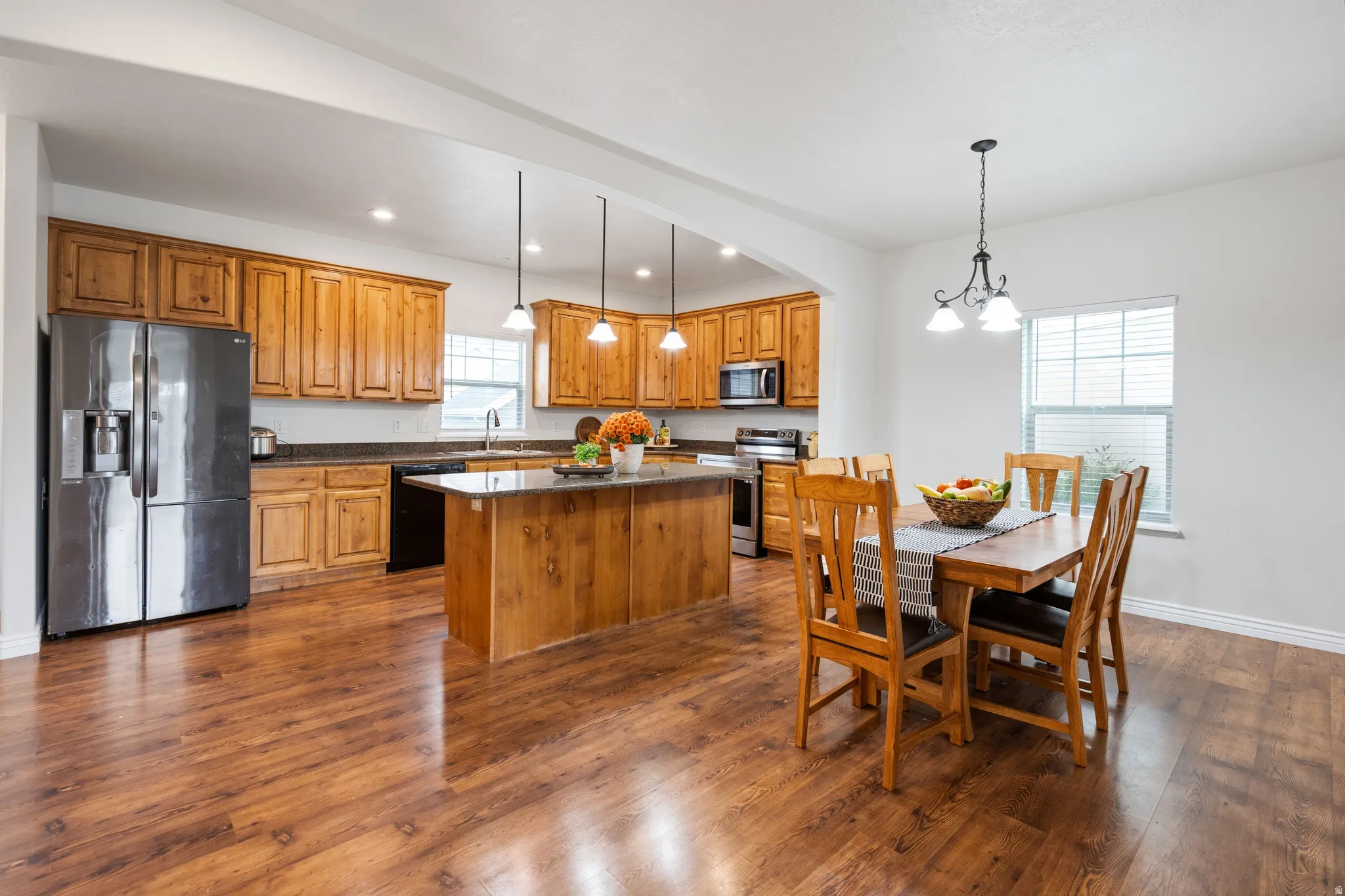 Expansive wood-finish flooring throughout, complemented by a kitchen island with pendant lighting