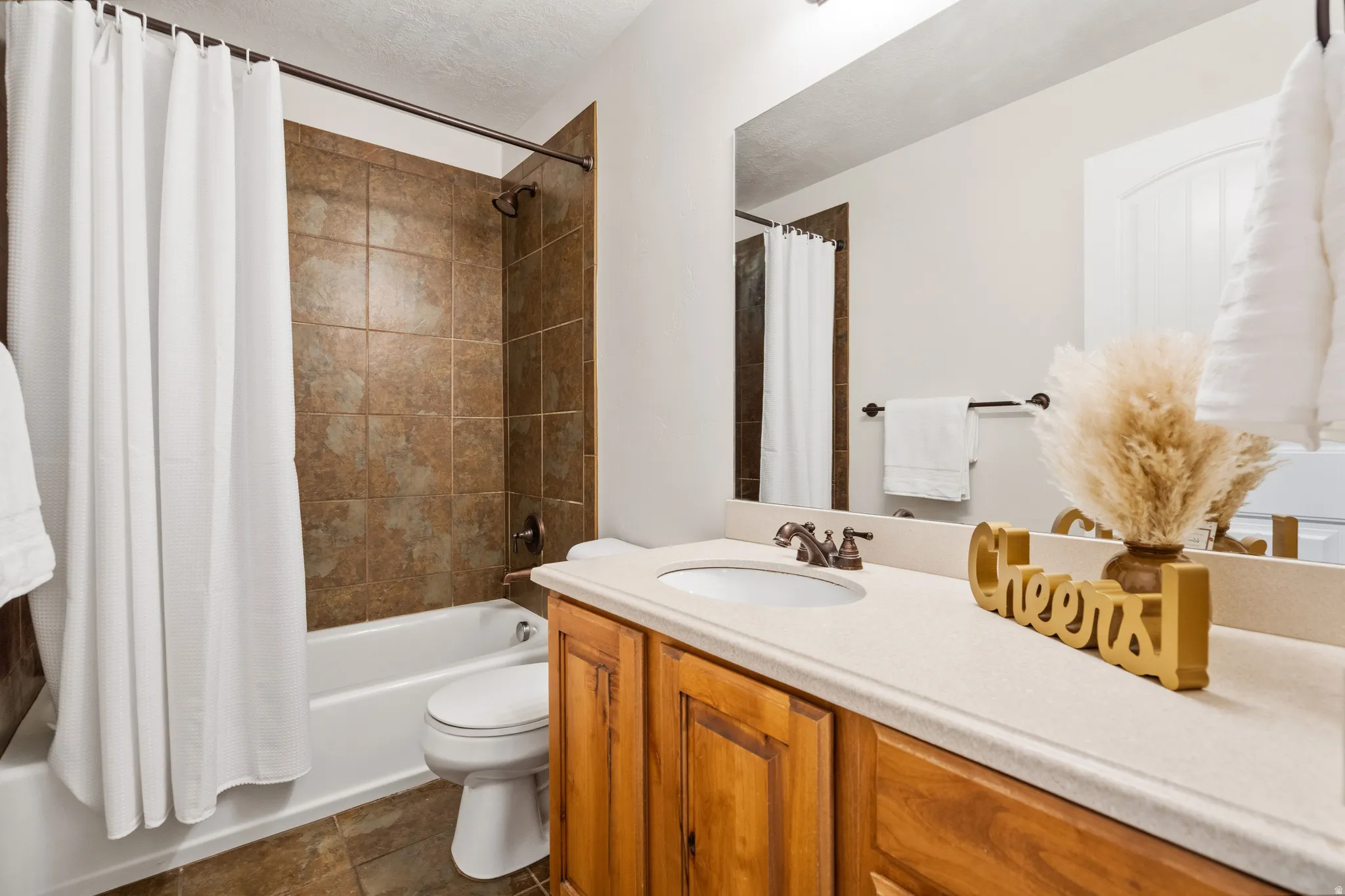 Wood-finish vanity with a single basin sink and bronze-finish faucet