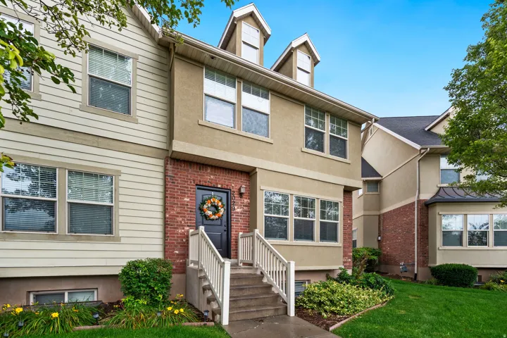 Multi-level townhome with stone steps, a dark entry door, and a combination of brick, stucco, and horizontal siding