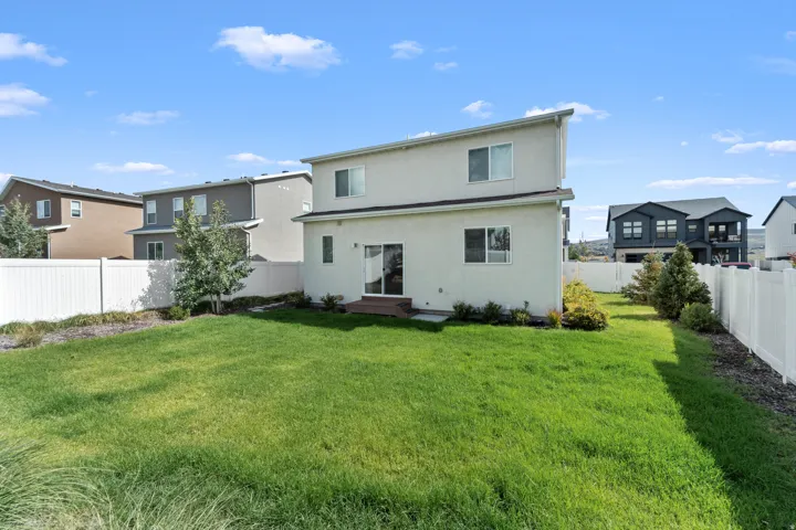 Expansive green space featuring a privacy fence, rear entry door, and ground-level outdoor surface
