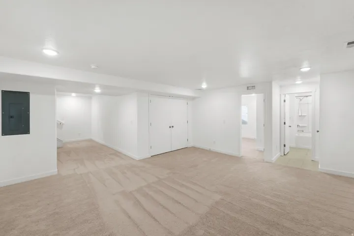 Expansive carpeted area with recessed lighting, double-door closet, and access to a tiled bathroom with a tub/shower combination