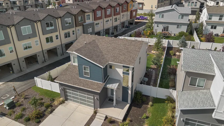 Contemporary exterior with blue and gray siding, attached garage with frosted-panel door, front porch with gray columns, and a landscaped front yard