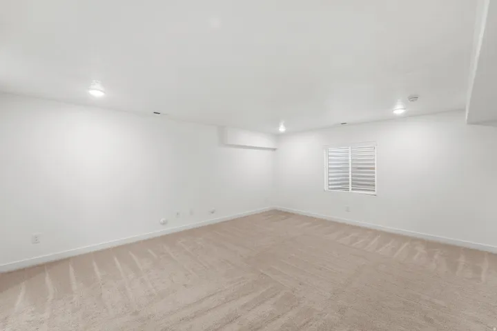 Recessed lighting, neutral carpeting, window with horizontal blinds, and white painted walls