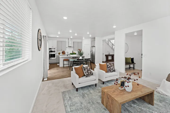 Recessed lighting illuminates the open-concept living space with light-toned walls and carpet