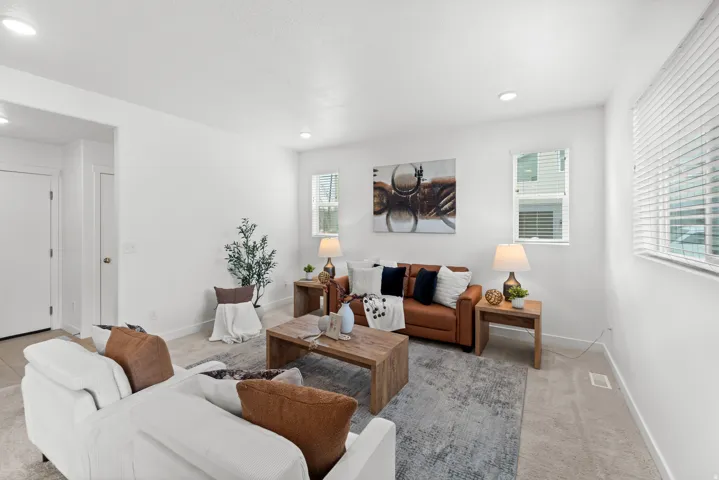 Carpeted living area with white walls, recessed lighting, and multiple windows