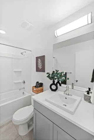 Bathroom featuring a bathtub with shower, toilet, and vanity with an integrated sink and base cabinetry