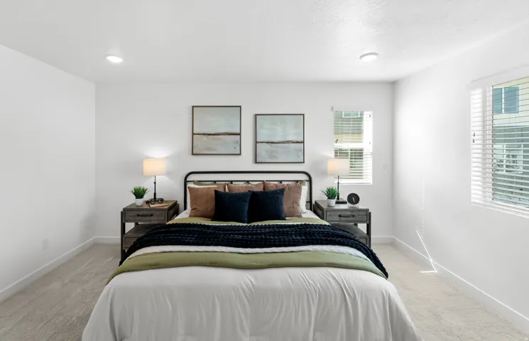 Bright bedroom featuring two windows with blinds, recessed lighting, and soft carpeting