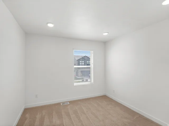 Recessed ceiling lighting, neutral carpet flooring, white painted walls, and a window with blinds