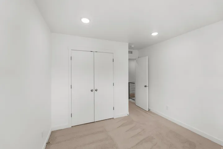 Plush carpet flooring, recessed lighting, white walls, and a bi-fold closet door
