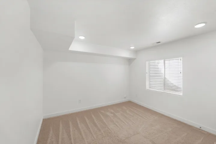 Recessed lighting, neutral-toned carpeting, white walls, and a window with blinds