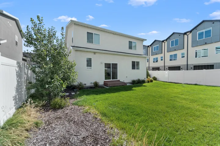 Expansive backyard featuring a manicured lawn, a small privacy tree, and a built-in deck