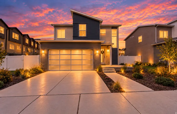 Modern exterior with mixed material facade, concrete driveway, translucent panel garage door, and dedicated landscaping with accent lighting