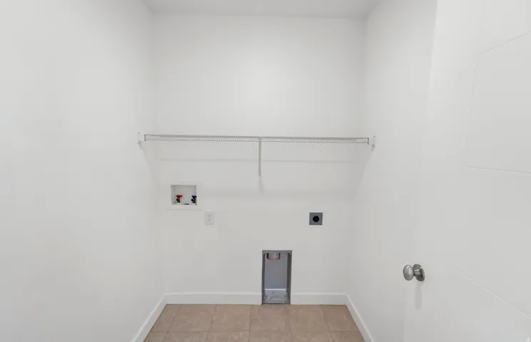 Laundry area featuring tile flooring, a wire shelf, and appliance hookups