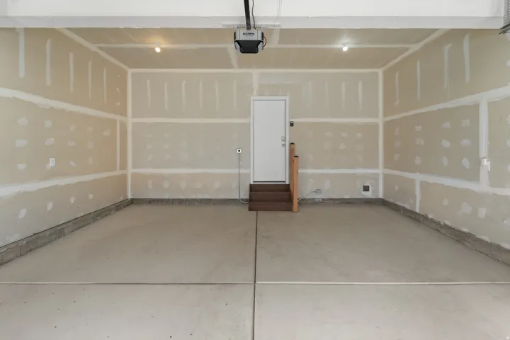Concrete flooring, interior access door, wood-finish steps, and overhead lighting