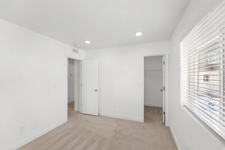 Recessed lighting, neutral carpeting, window with blinds, and white interior doors