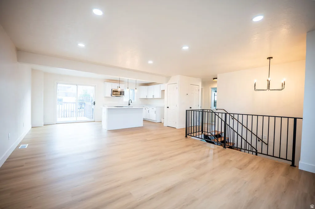 Open-concept living area featuring wood-finish flooring, recessed lighting, and a modern chandelier