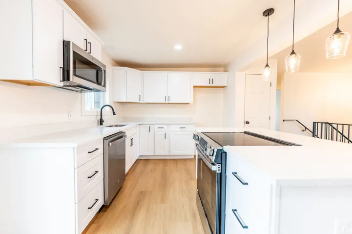 Kitchen featuring white cabinetry, light-toned wood-finish flooring, white countertops, and stainless steel appliances