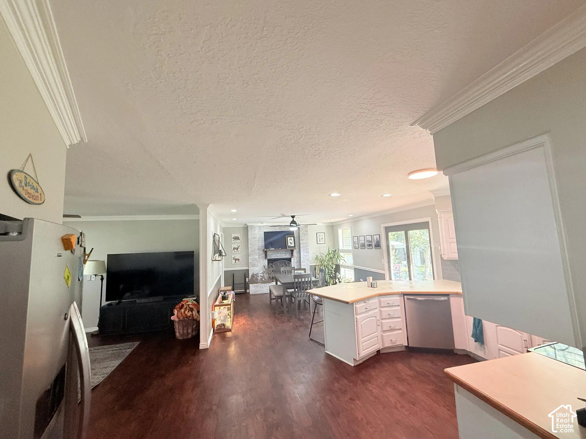 Hardwood-finish flooring, crown molding, white cabinetry, integrated dishwasher, and light wood-finish countertops