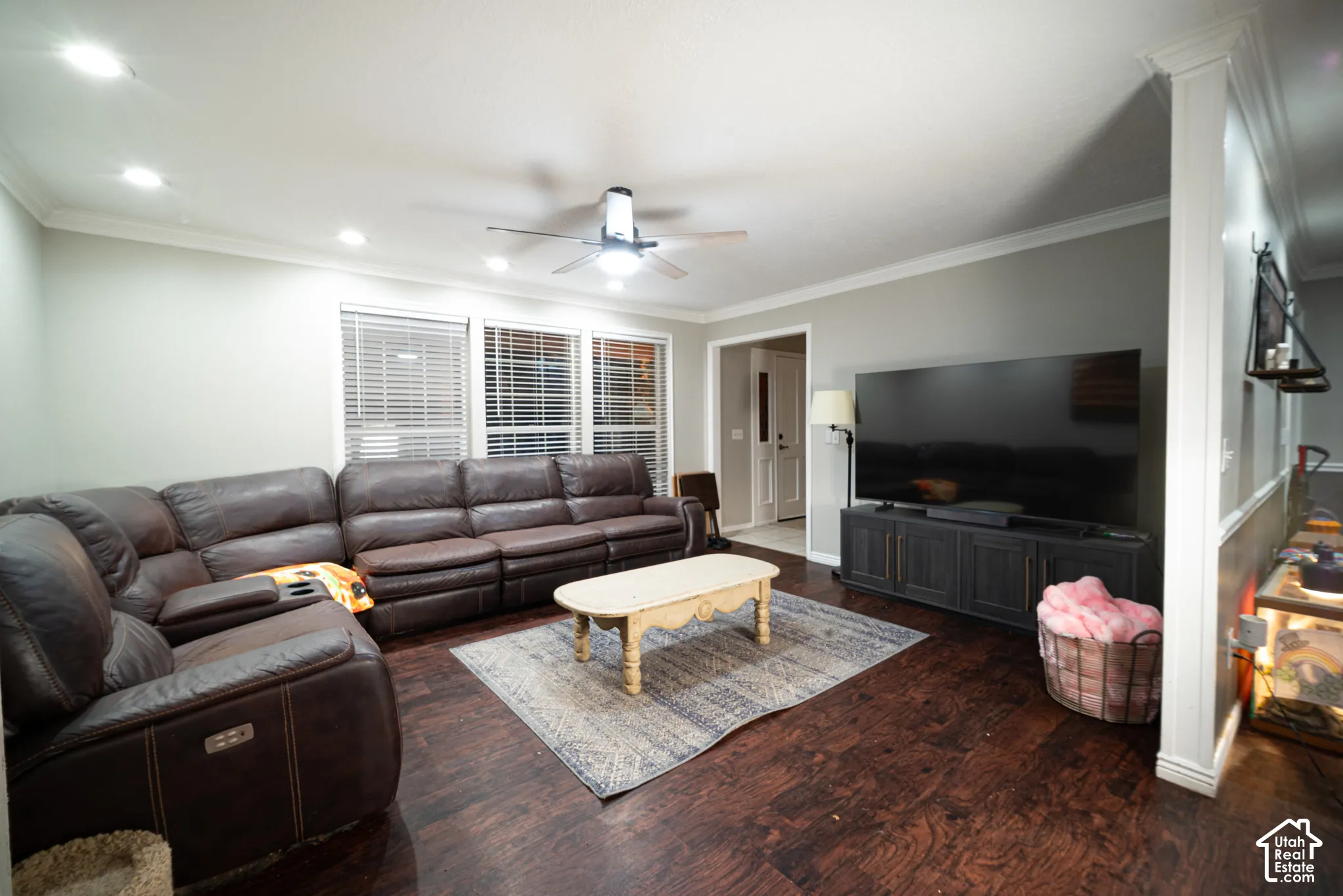 Wood-finish flooring, recessed lighting, crown molding, ceiling fan, and multiple windows with blinds
