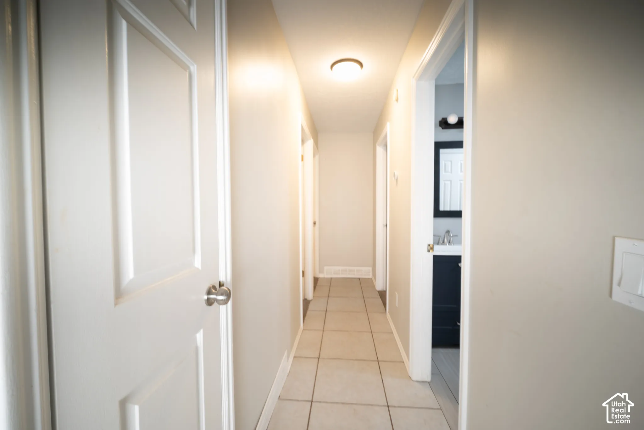 Hallway with light beige wall paint, tile flooring, and flush-mount ceiling light