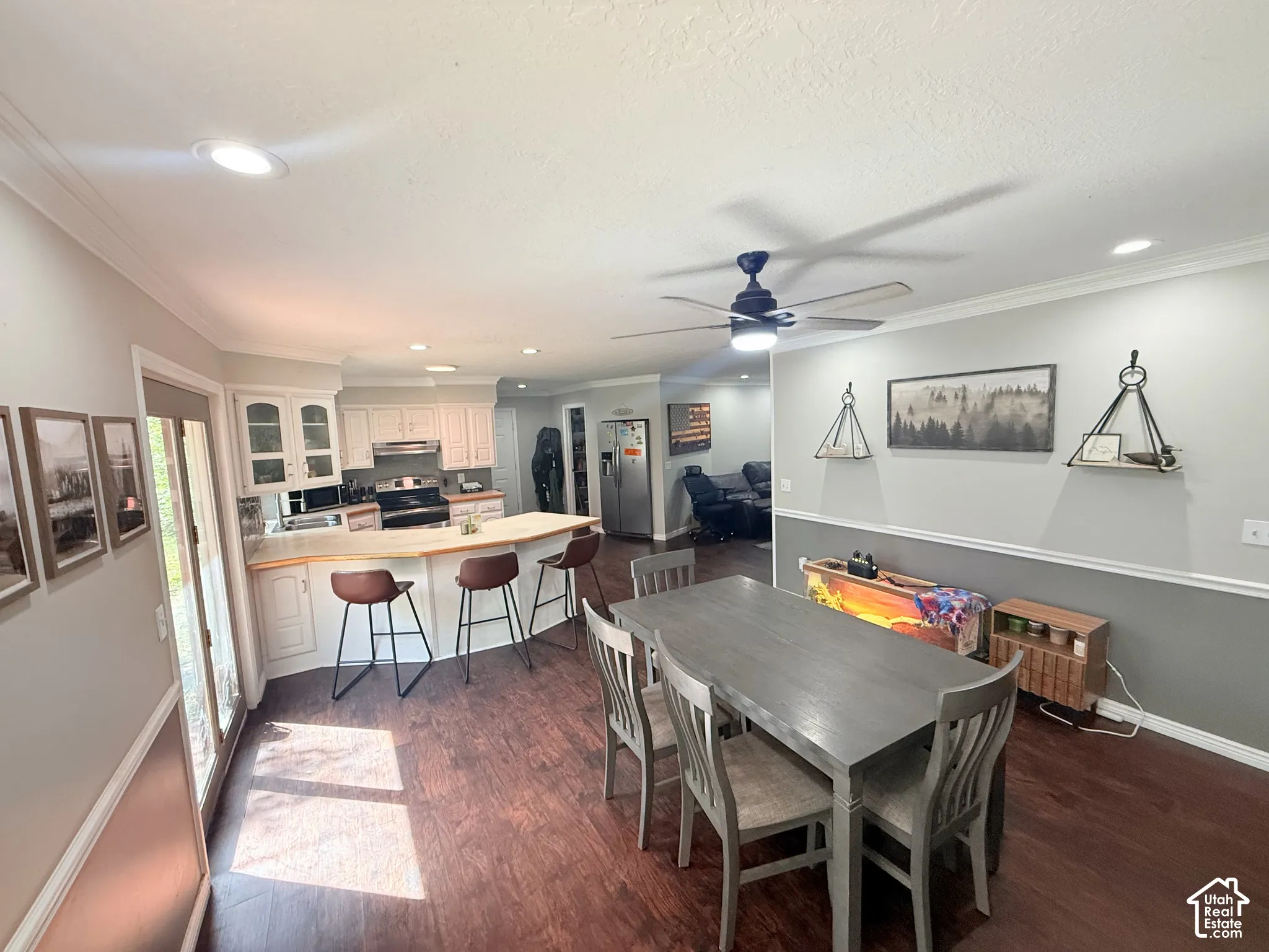 Open-concept kitchen and dining area featuring wood-finish flooring, white cabinetry, recessed lighting, and a ceiling fan