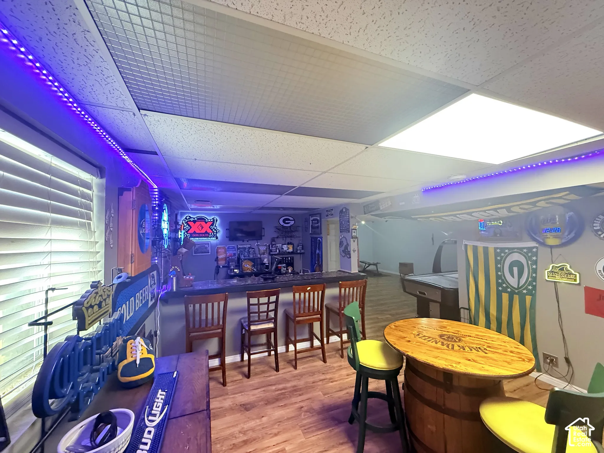 Wood-finish flooring with a built-in bar, recessed lighting, and a drop ceiling