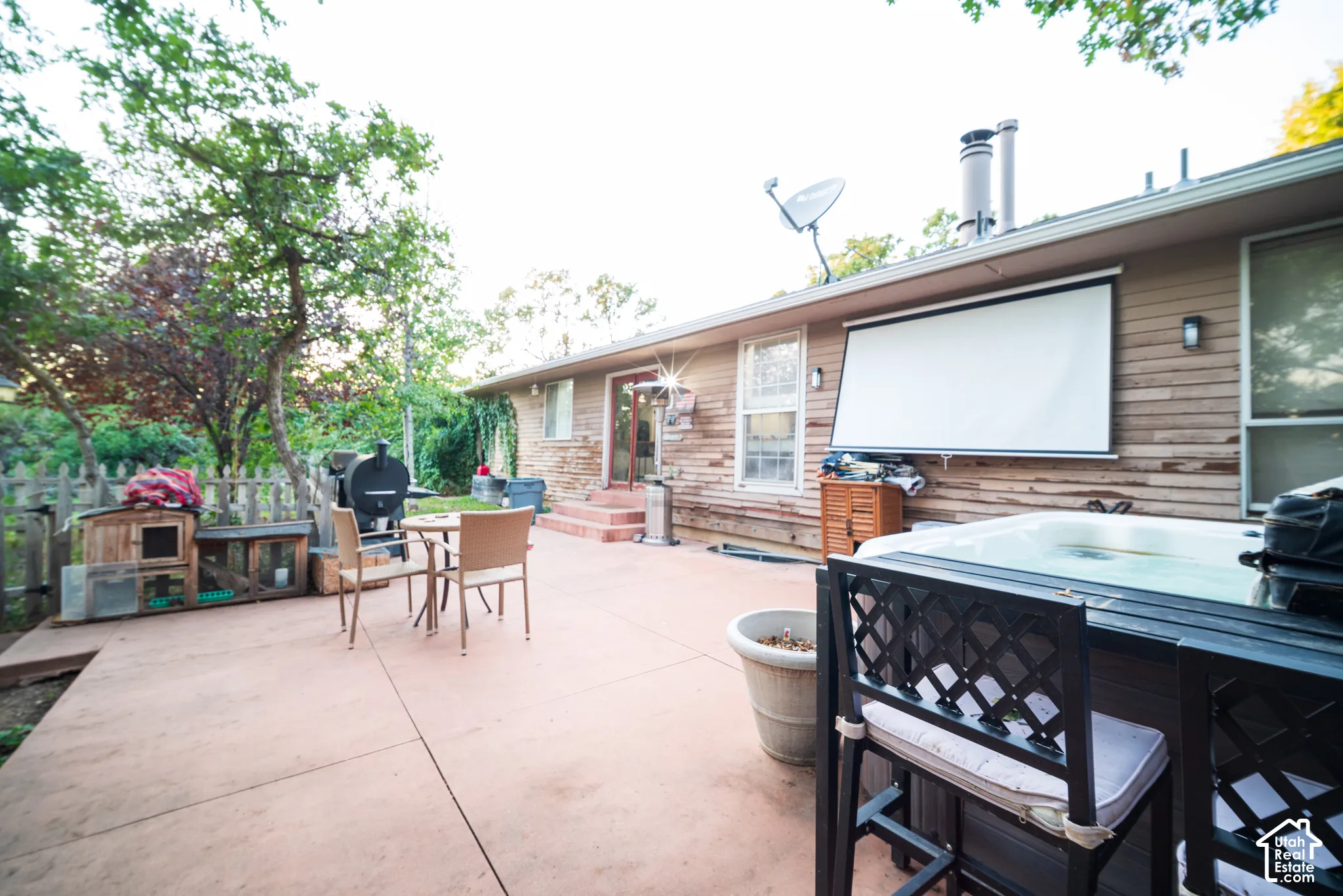 Expansive concrete patio with built-in hot tub, retractable projection screen, and wood plank siding