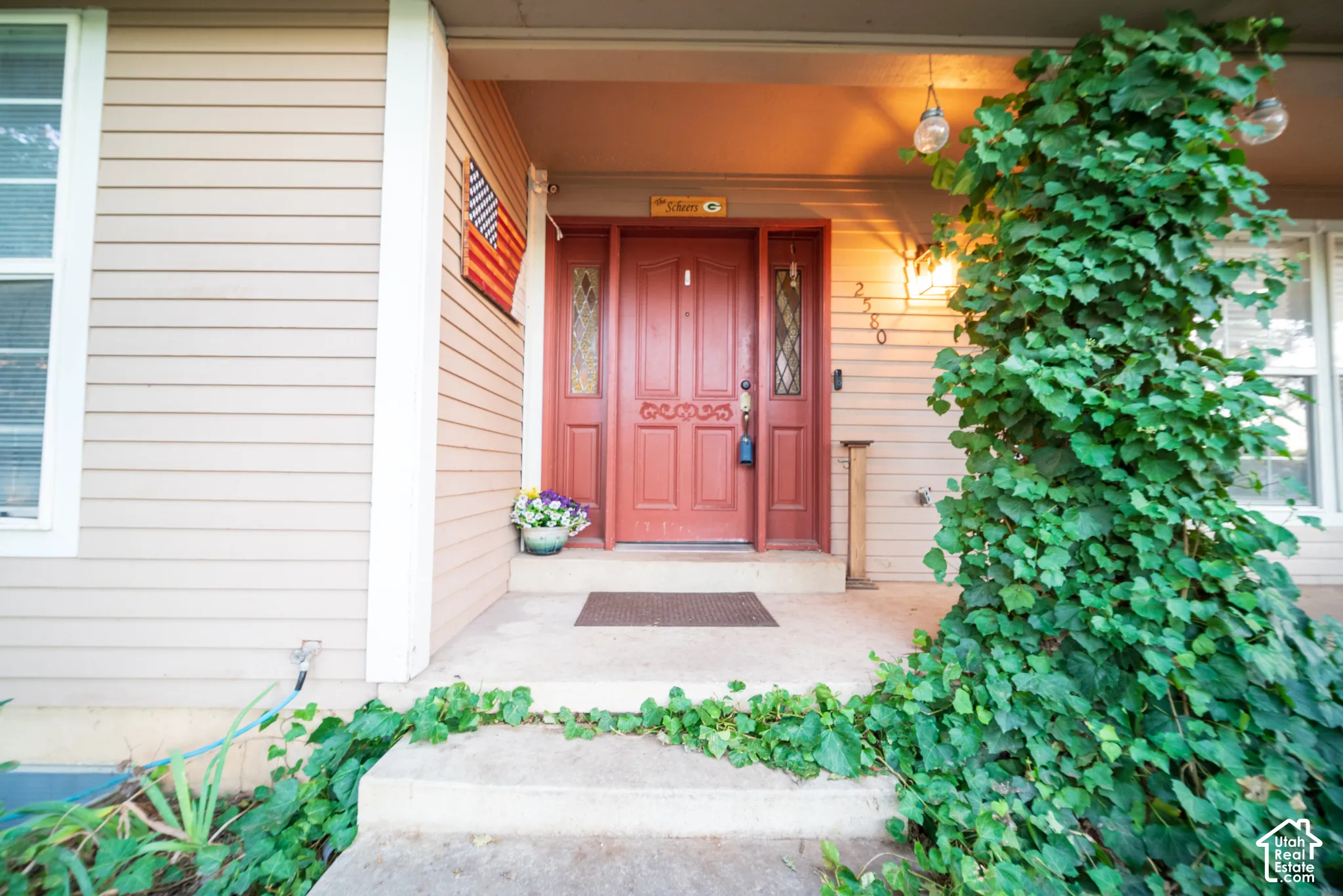 Inviting entry with a red panel door, decorative glass inserts, and a covered porch
