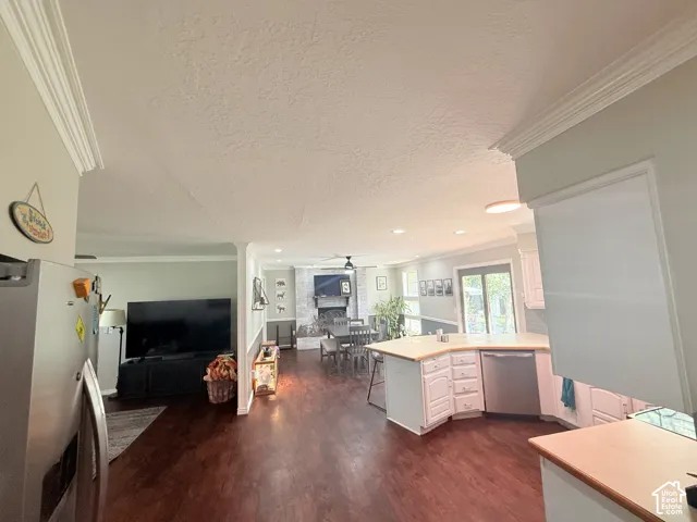 Hardwood-finish flooring, crown molding, white cabinetry, integrated dishwasher, and light wood-finish countertops