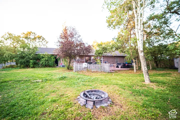 Expansive backyard with a stone-lined fire pit, mature trees, and a private patio area