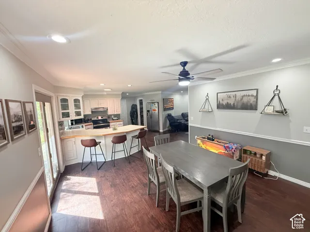Open-concept kitchen and dining area featuring wood-finish flooring, white cabinetry, recessed lighting, and a ceiling fan