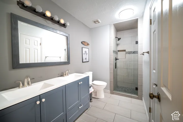Dual sink vanity with blue cabinetry, framed mirror, and integrated lighting