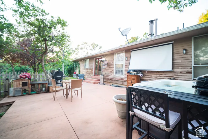 Expansive concrete patio with built-in hot tub, retractable projection screen, and wood plank siding