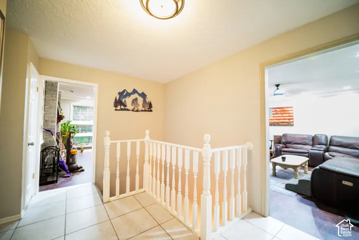 White spindle railing, tiled flooring, and recessed ceiling light fixture