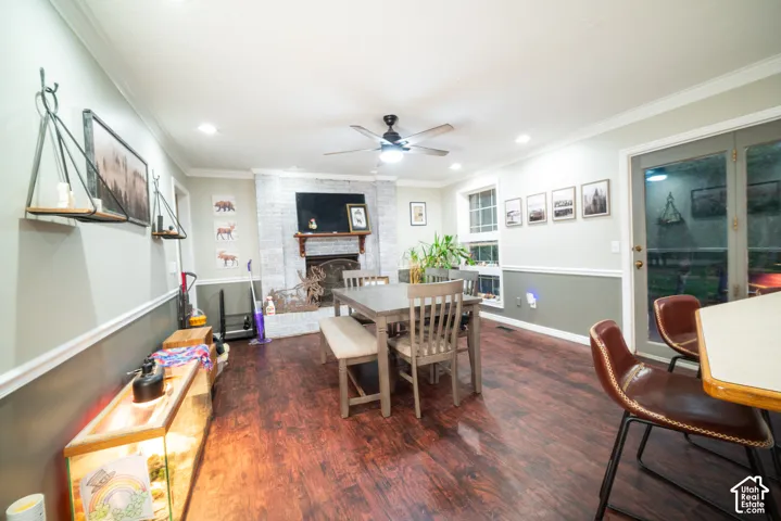 Wood-finish flooring, recessed lighting, ceiling fan, white brick fireplace with mantel, and glass-paned double doors